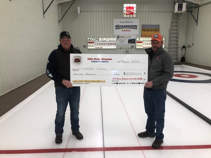 Milk River Kinsmen volunteers present a novelty cheque from the Corvette Raffle to the Warner Curling Club at a curling rink